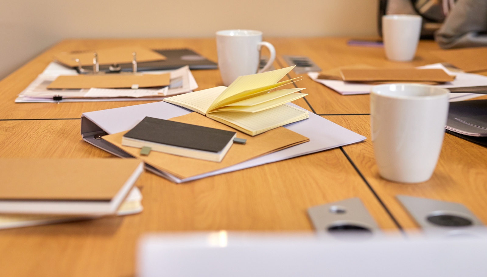 Unsorted business cards and scattered notes piled next to a laptop after a networking event.